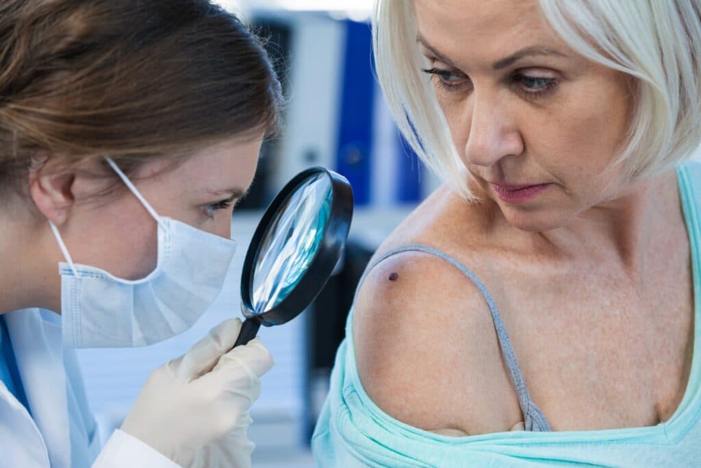 Dermatologist checking mole on woman’s shoulder